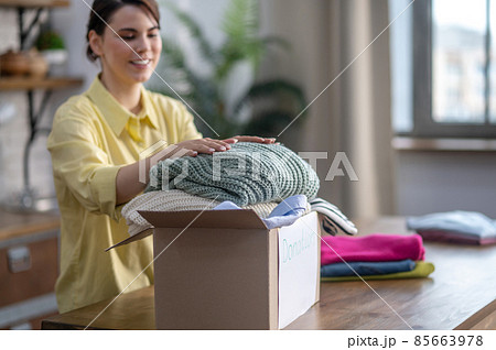Happy lady placing sweaters in the carton 85663978