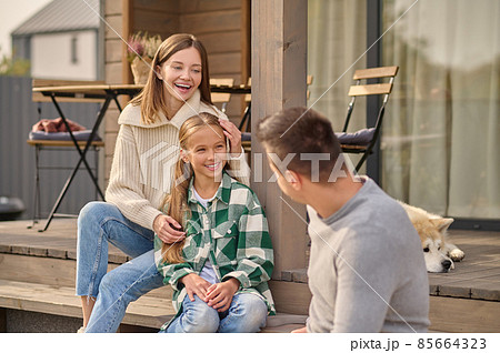 Woman touching daughter looking at man sitting on steps 85664323