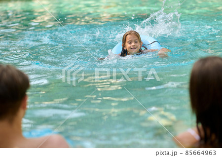 Cute girl and her parents spending time at the swimming pool 85664963