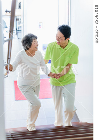 階段を上るシニア女性と介護スタッフ　撮影協力：中央工学校附属日本語学校 85665018