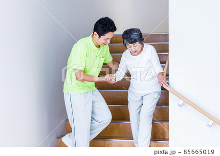 階段を降りるシニア女性と介護スタッフ　撮影協力：中央工学校附属日本語学校 85665019