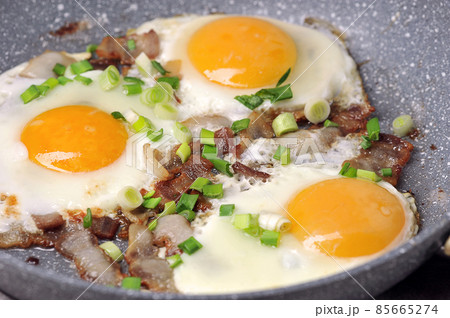 fried eggs with bacon and green onions in a frying pan fried eggs with bacon and green onions in a frying pan 85665274