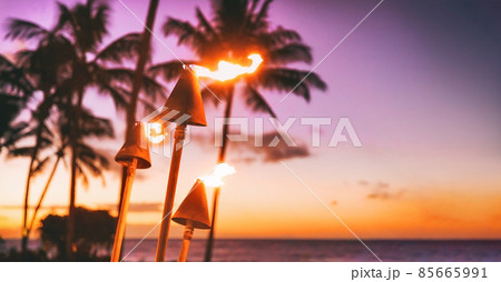 Hawaii luau beach party at sunset. Hawaiian tiki torches lighted up with fire at luxury resort hotel restaurant. Panoramic banner of hawaiian aloha spirit 85665991
