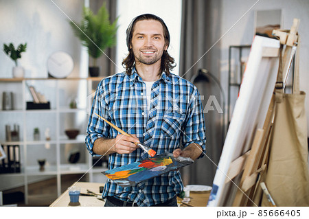 Artist smiling on camera with palette and brush in hands Artist smiling on camera with palette and brush in hands 85666405
