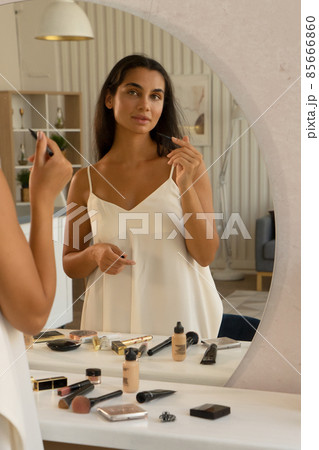 brunette woman with long straight dark hair and clean skin doing make up routine 85666860