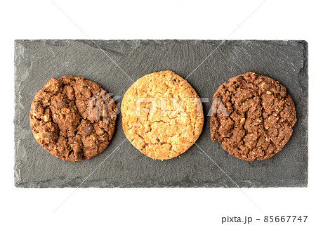 Top view of different varieties of granola cookies on a stone board for serving. Top view of different varieties of granola cookies on a stone board for serving. 85667747