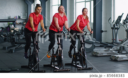 Group of girls performs aerobic training workout cardio routine on bike simulators, cycle training 85668383