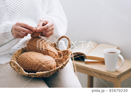 A middle-aged woman is engaged in home handicraft knitting, knitting with threads. Home activity hobby during free time A middle-aged woman is engaged in home handicraft knitting, knitting with threads. Home activity hobby during free time 85670230