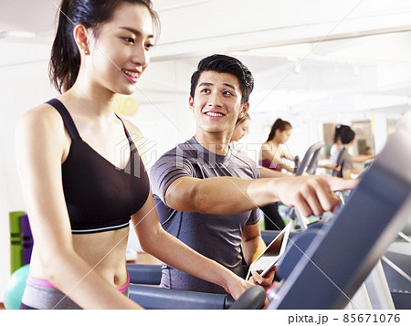 young asian woman running on treadmill coached by young trainer young asian woman running on treadmill coached by young trainer 85671076