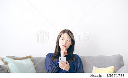 スマホを見て悩む女性 85671733