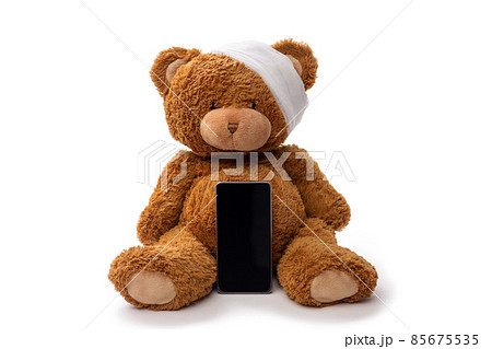 teddy bear toy with bandaged head and smartphone 85675535
