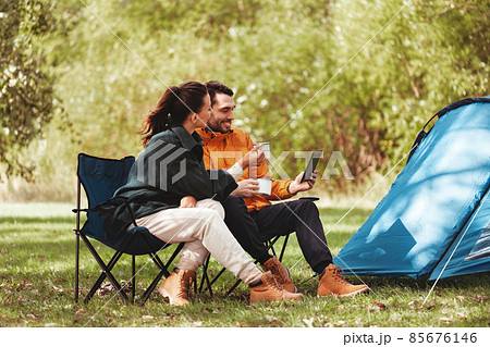 couple with tablet pc drinking tea at tent camp 85676146