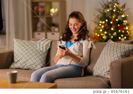 woman with smartphone at home on christmas 85676161