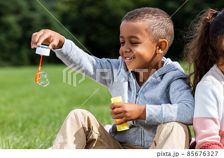 happy children blowing soap bubbles at park happy children blowing soap bubbles at park 85676327