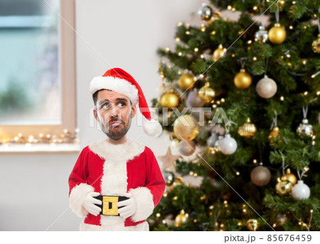 sad man in santa claus costume over christmas tree sad man in santa claus costume over christmas tree 85676459