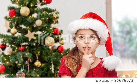 girl making shh gesture over christmas tree girl making shh gesture over christmas tree 85676672