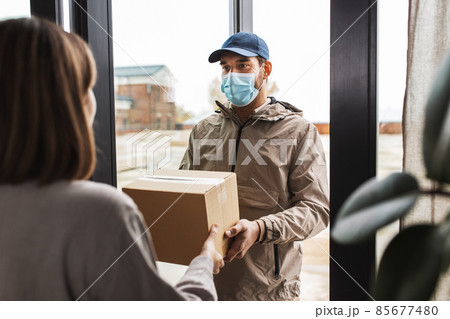 delivery man in mask giving parcel to customer 85677480
