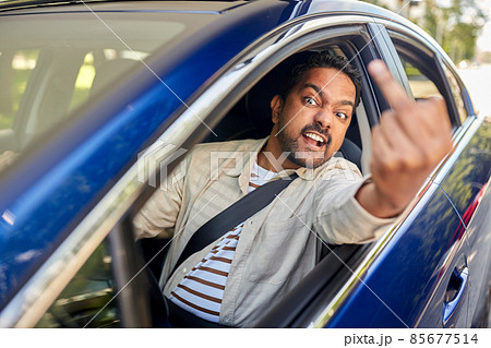 angry man driving car and showing middle finger 85677514