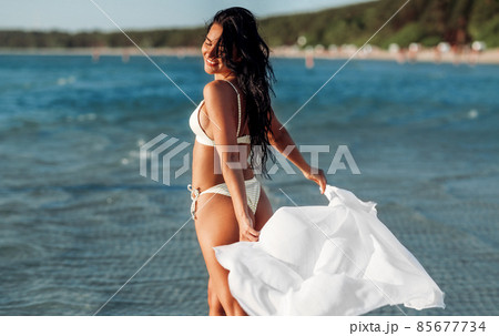 woman in bikini swimsuit with cover-up on beach woman in bikini swimsuit with cover-up on beach 85677734