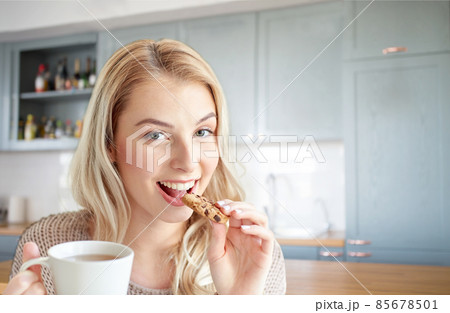 happy woman with tea eating cookie on kitchen happy woman with tea eating cookie on kitchen 85678501