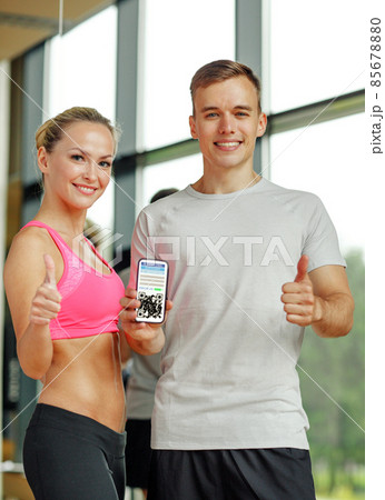 happy couple with qr code on smartphone in gym 85678880