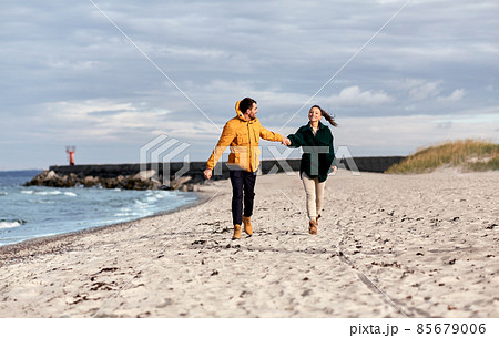 couple running along autumn beach 85679006