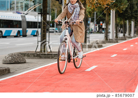 woman riding bicycle along red bike lane in city 85679007
