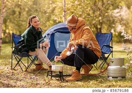 couple drinking beer and cooking food at tent camp couple drinking beer and cooking food at tent camp 85679186