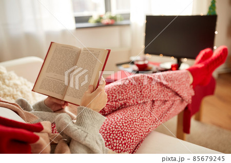 young woman reading book at home on christmas 85679245