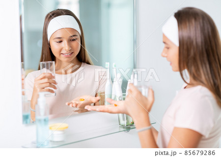 teenage girl taking cod liver oil at mirror teenage girl taking cod liver oil at mirror 85679286