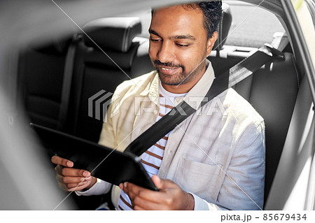 indian male passenger with tablet pc in taxi car 85679434
