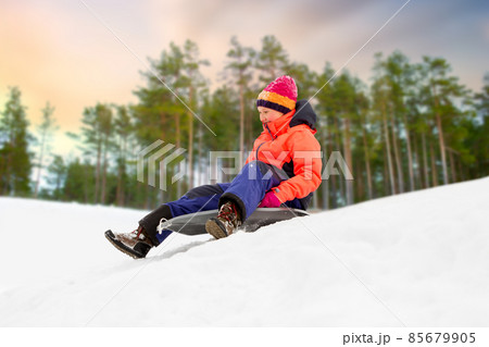 happy girl sliding down on sled in winter 85679905