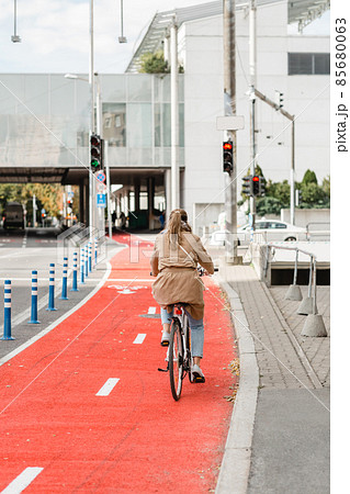 woman cycling along red bike lane road in city woman cycling along red bike lane road in city 85680063