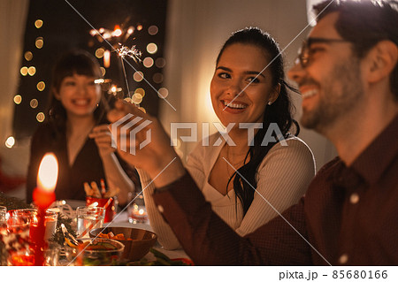 happy friends with sparklers at christmas dinner happy friends with sparklers at christmas dinner 85680166