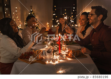 happy friends with sparklers at christmas dinner 85680196