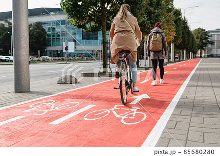 woman cycling behind pedestrian along bike lane 85680280