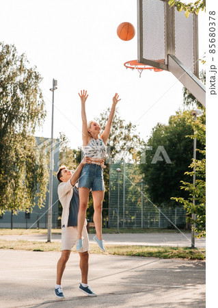 happy couple playing on basketball on playground 85680378