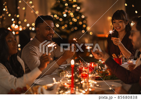 happy friends with sparklers at christmas dinner 85680838