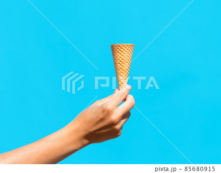 close up of hand holding empty ice cream cone 85680915