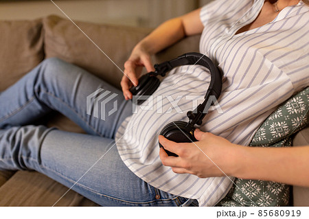 pregnant woman with headphones on her belly 85680919