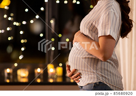 close up of pregnant woman at window at home 85680920