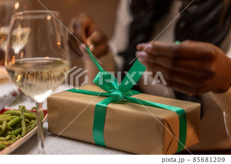 woman opening christmas gift at dinner party 85681209