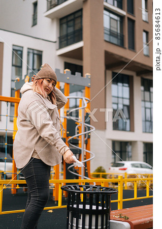 Vertical shot of overweight woman in warm hat and jacket using antibacterial wet wipes to clean disinfect hands and throws them in trash 85684613