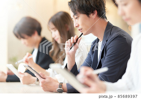手にしたタブレットにメモをとるセミナー受講生 手にしたタブレットにメモをとるセミナー受講生 85689397
