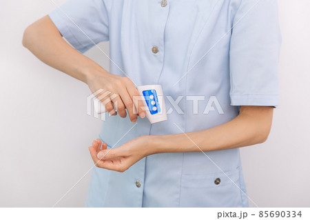 Temperature measurement gun in doctor hands. Close-up shot of doctor wearing protective surgical mask ready to use infrared isometric thermometer gun to check body temperature for virus symptoms. 85690334