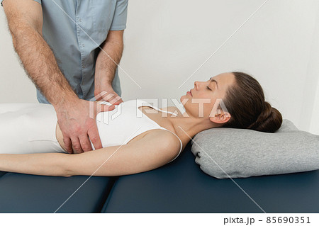 Osteopathic belly massage. Female patient receiving osteopathic belly or tummy treatment. Osteopathic manipulation and therapy. Manual therapist manipulates woman's belly. Osteopathic belly massage. Female patient receiving osteopathic belly or tummy treatment. Osteopathic manipulation and therapy. Manual therapist manipulates woman's belly. 85690351
