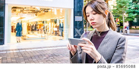 東京丸の内でスマホで地図を確認する若いビジネスウーマン 85695088