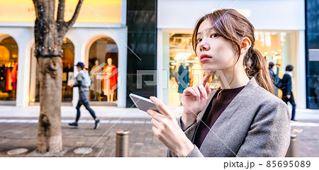東京丸の内でスマホで地図を確認する若いビジネスウーマン 85695089