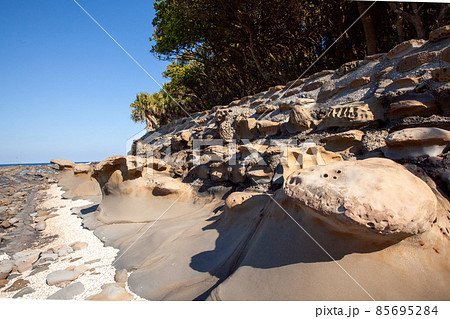 青空の下に隆起海床できた上に貝殻が蓄積しできた島に神様が祀られその周りには、鬼の洗濯岩や侵食さ波状岩 85695284