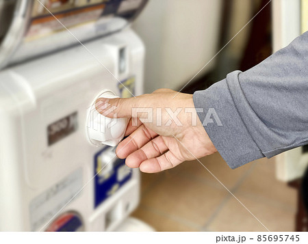カプセルトイのダイヤルを回す男性の手元 85695745